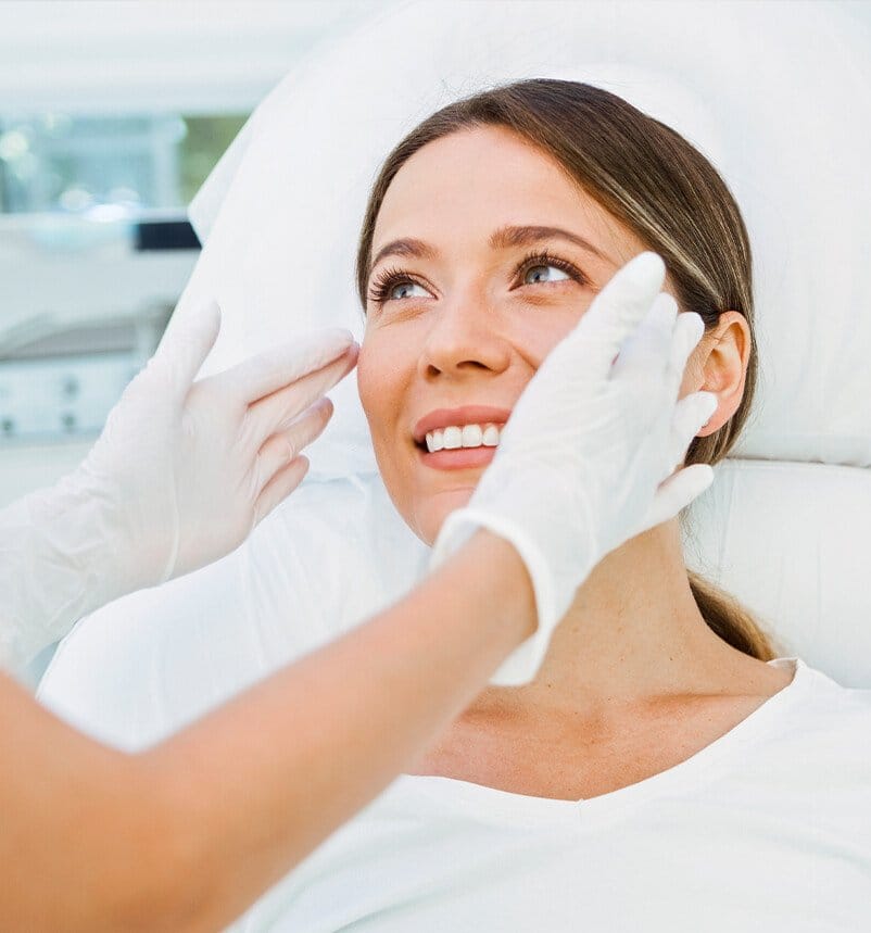 woman smiling as a staff member touches her face