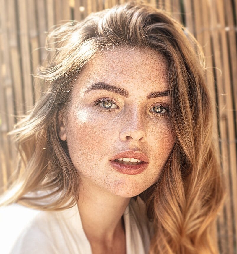 blond woman with freckles and blue eyes posing for a picture