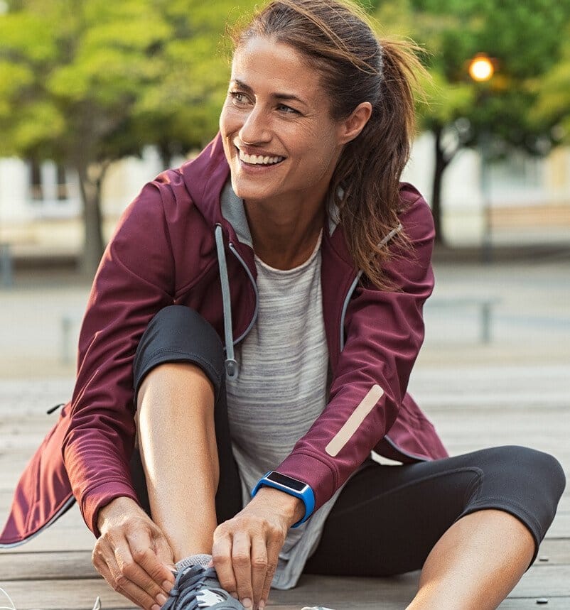 woman sitting on the ground tying up her shoe
