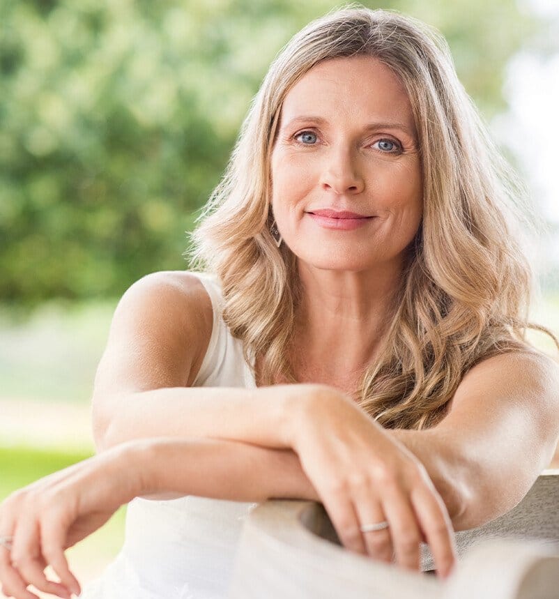 blond woman sitting on a bench with her arms crossed