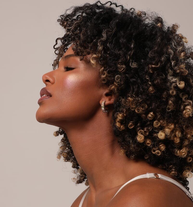 a close up of a woman with curly hair and a white top