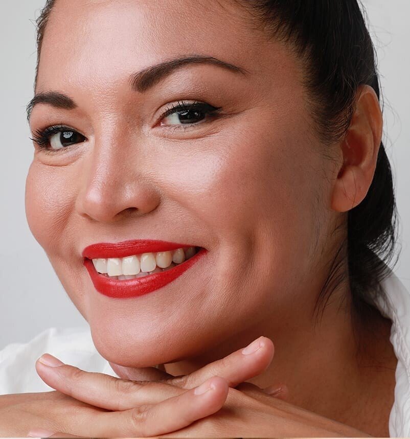 smiling woman with red lipstick and a white shirt posing for a picture