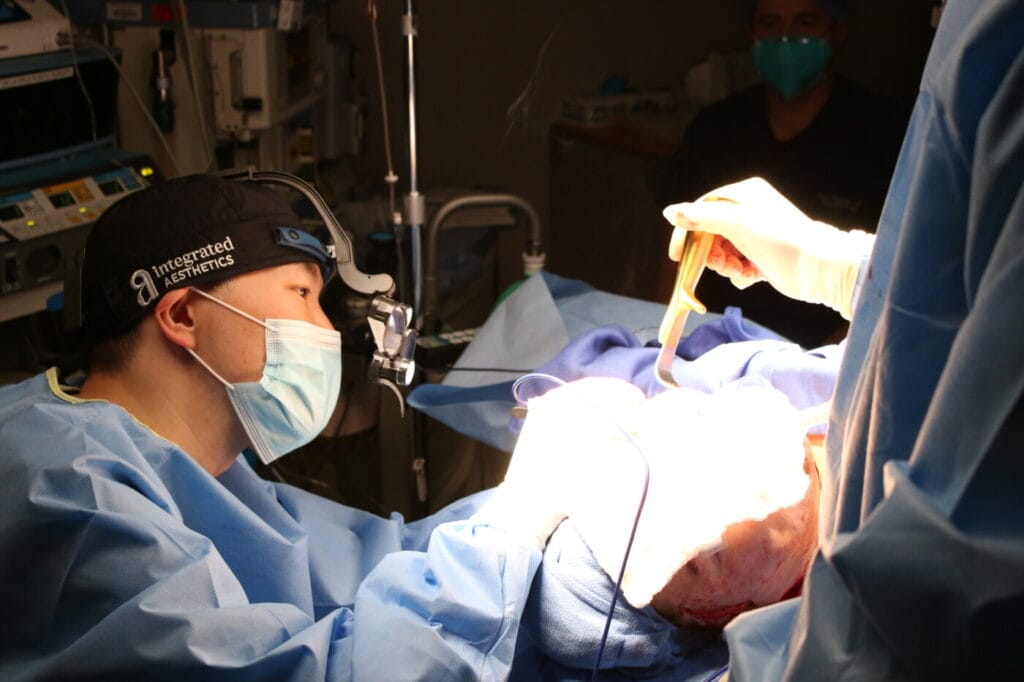 Board-certified plastic surgeon Dr. Young Cho performing an advanced extended facelift surgery in the accredited surgical suite at Integrated Aesthetics in Spring, TX.